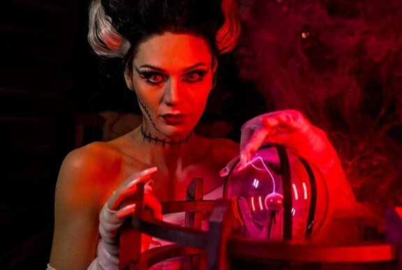 A woman dressed in a Halloween costume to look like Frankenstein's wife, with a crystal ball and smoke curling around her.