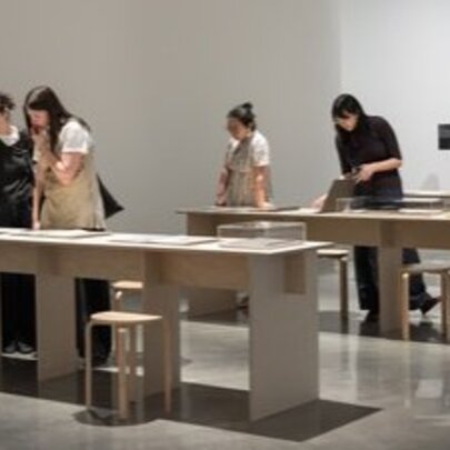 People gathered to look at display cases in a gallery setting.