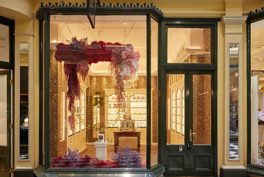 Looking into an ornate shopfront with elegant cabinets filled with bottles.