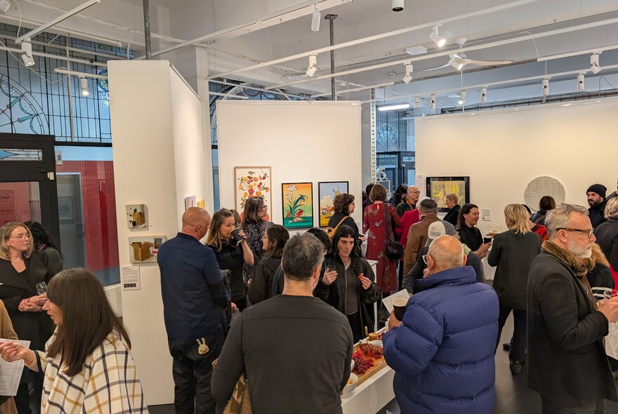 People in a a gallery space, mingling.