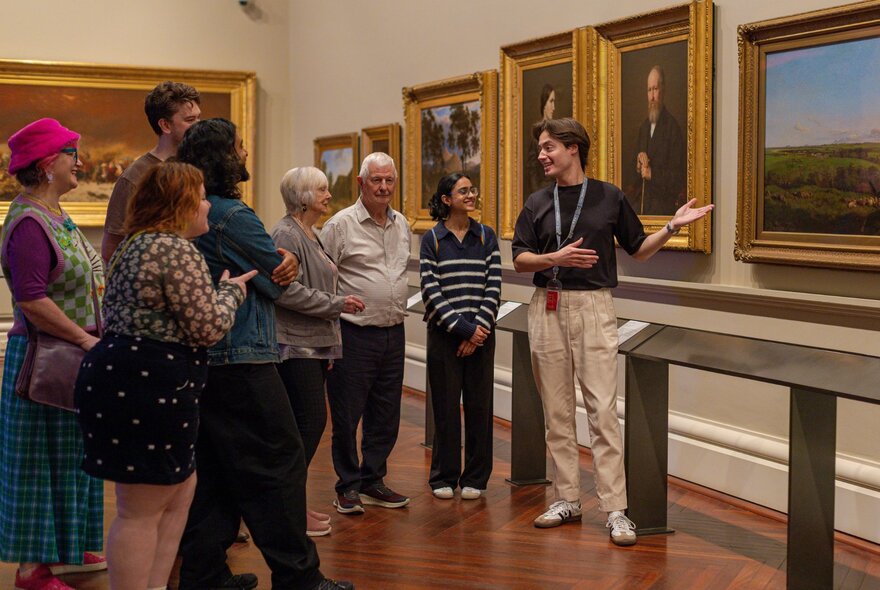 A group of people listening to a tour guide as they look at artworks in the archives of the State Library of Victoria.