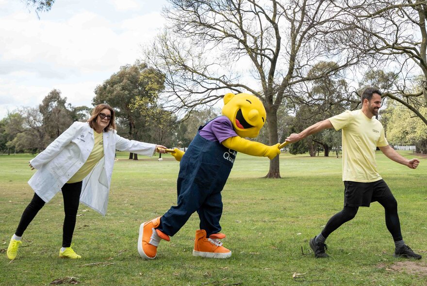 A community awareness and fundraising event in Princes Park, Carlton, with a mascot holding hands with a runner and a person in a white scientist's coat.
