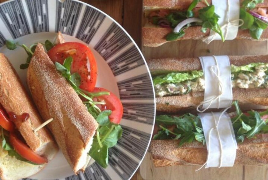 Plate with a halved tomato baguette, with other filled baguettes on the side.