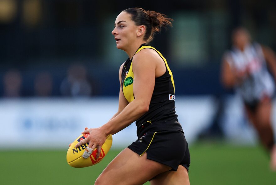Richmond footballer Monique Conti runs with the ball in her hands. 