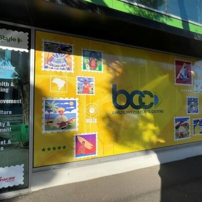 Exterior of a shopfront and cultural centre, with signage and text on the window of services on offer.