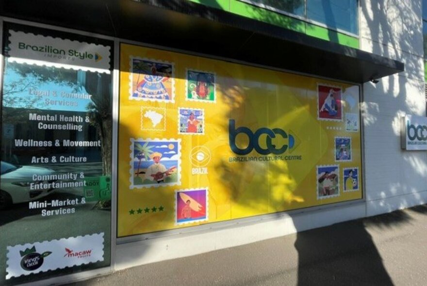 Exterior of a shopfront and cultural centre, with signage and text on the window of services on offer.