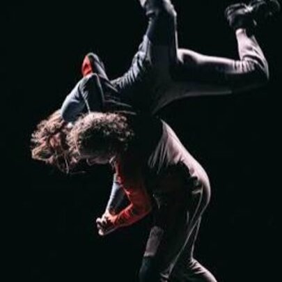 Dancers performing in spotlit darkness.