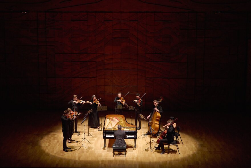 An ensemble playing on stage in a spotlight. 
