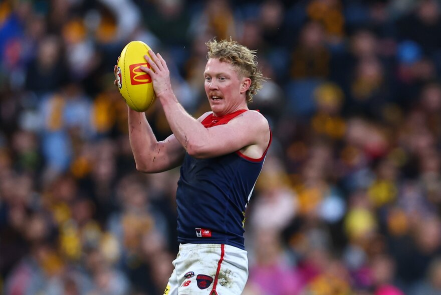 Melbourne  AFL football player catching a ball on the field during a match.