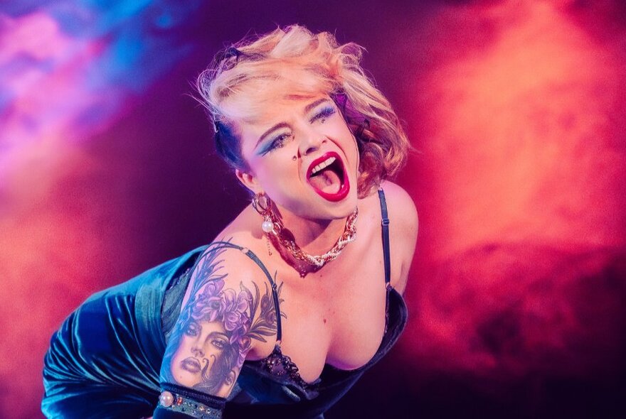 Performer showing decolletage performing under red lights.