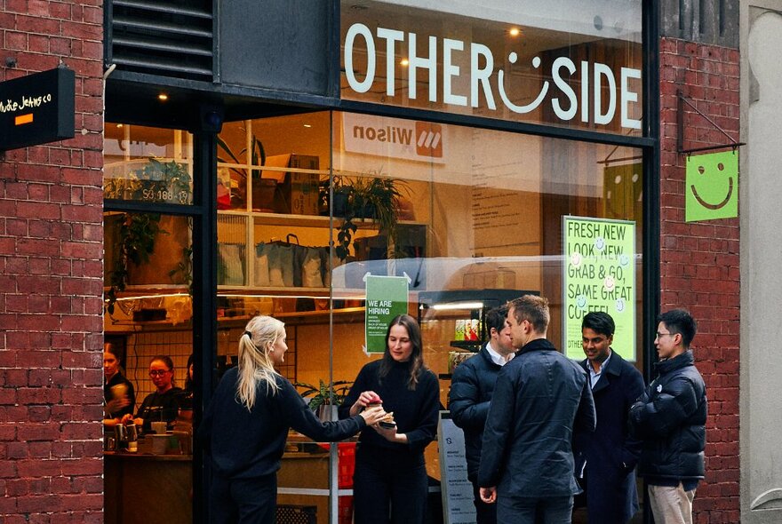 People standing outside a cafe waiting for takeaway coffee.