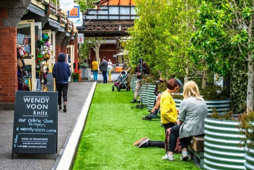 People sitting in a grassy area at Queen Victoria Market outside Wendy Voon Knits.