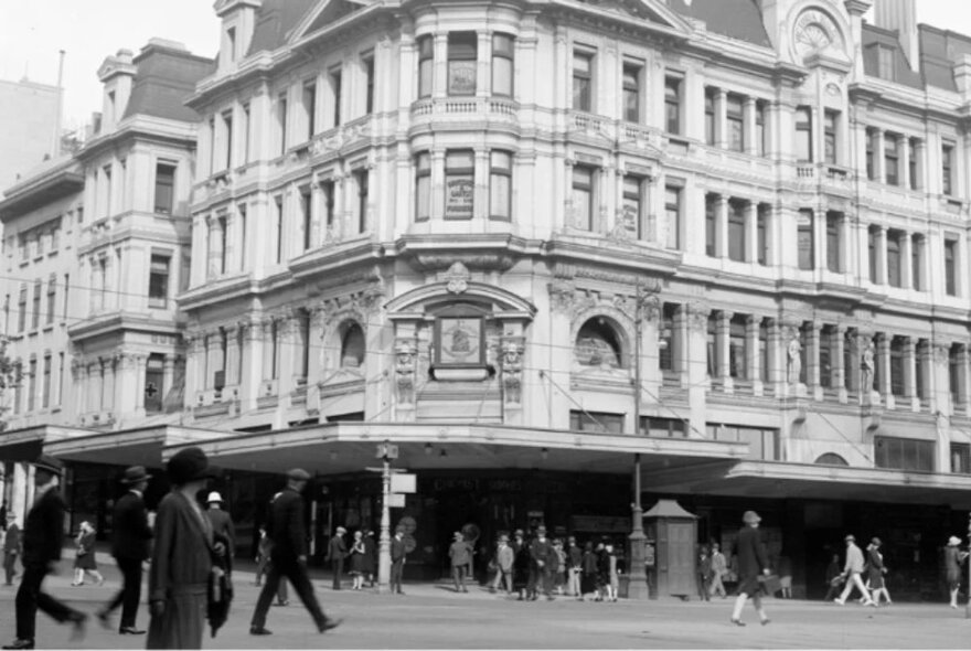 Melbourne street scene in the 1920s with people crossing the road in front of an ornate, now-demolished building.