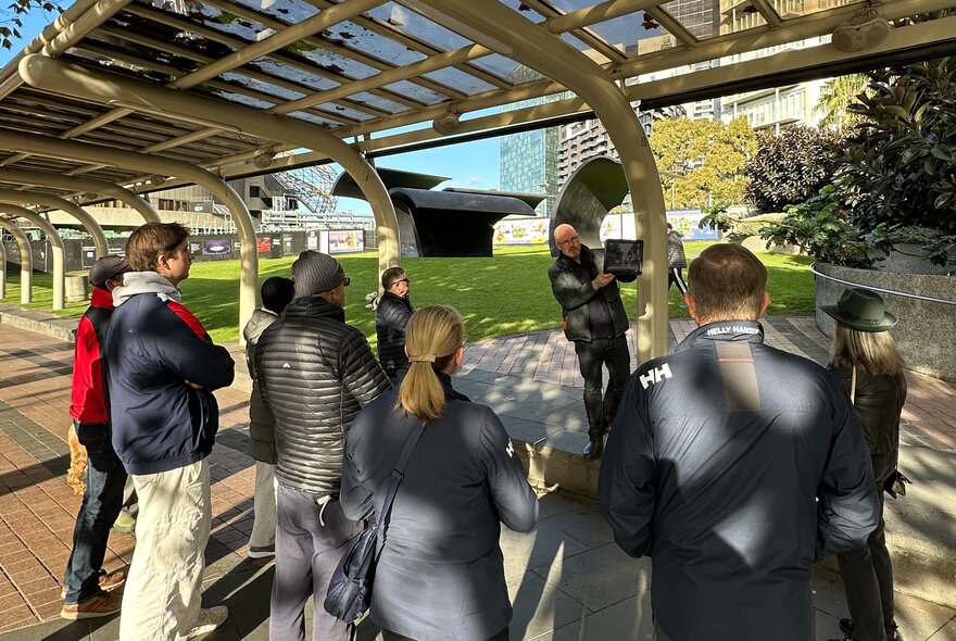 A group of people on an outdoor walking tour under a modern covered structure.