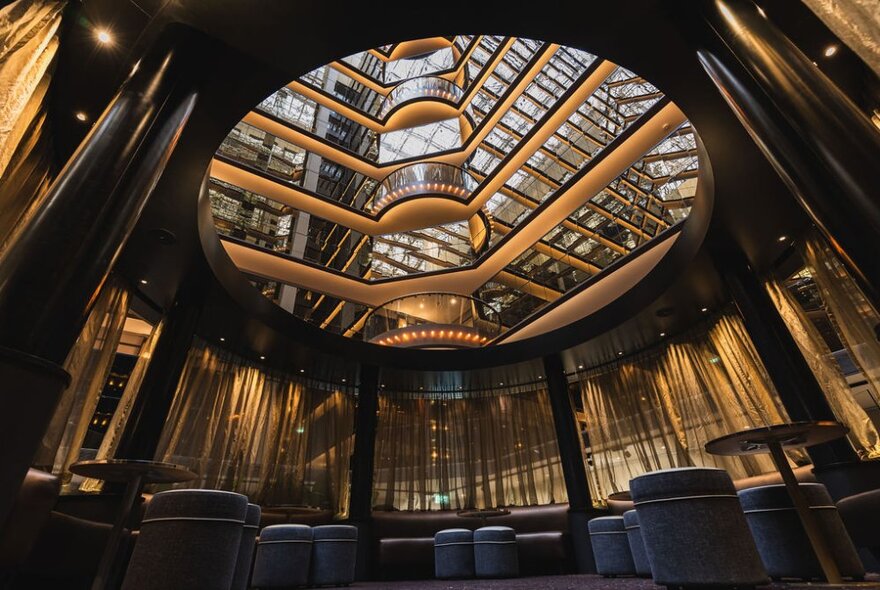 The Atrium on 35 Bar at Sofitel Melbourne on Collins, featuring plush seating under a mirrored fifteen-floor canopy looking up into a hotel atrium.