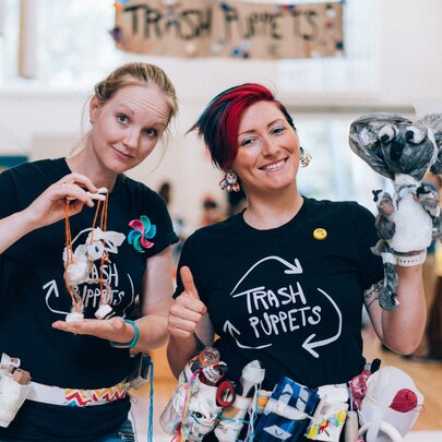 Two people from the professional puppetier company, Trash Puppets, holding puppets created entirely from rubbish.