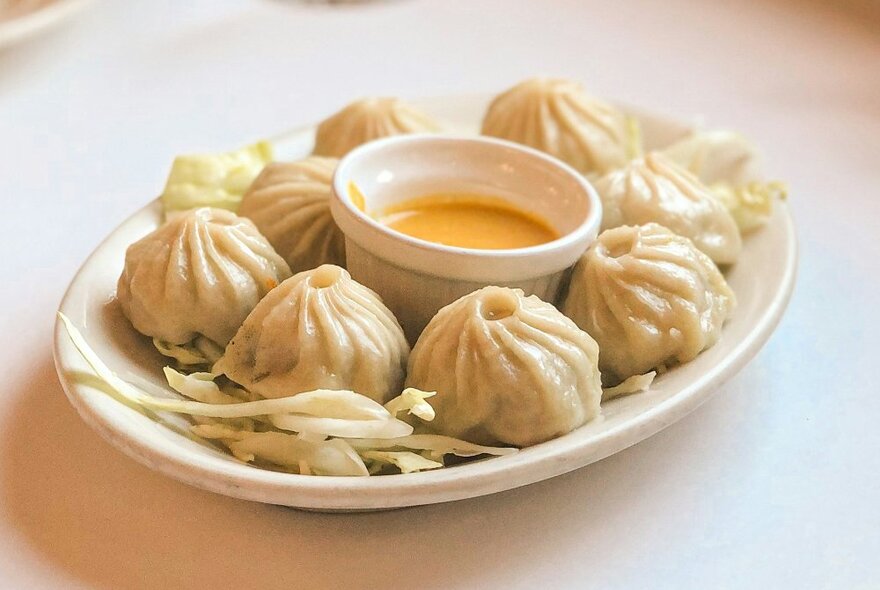 A plate of momos and dipping sauce.