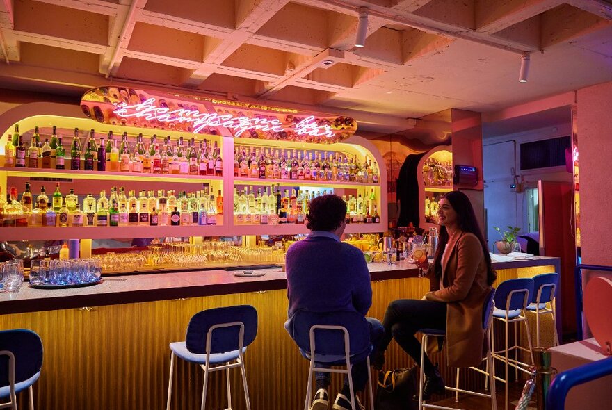 Two friends are sitting at a bar having a drink.