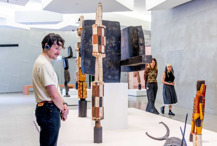 A visitor wearing headphones looking at and interacting with artwork at NGV Australia. 