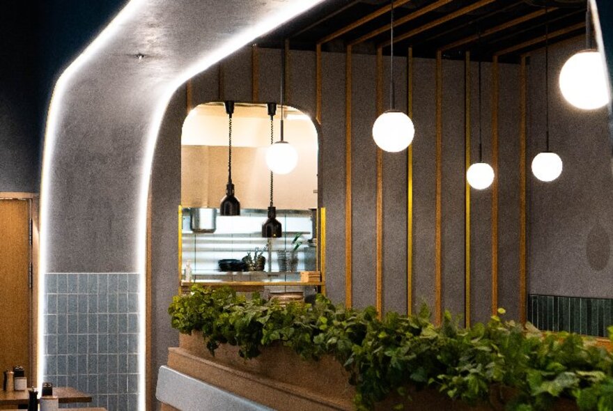 The sleek and stylish interior of Axil Coffee in Bourke Street, with hanging spherical lights, and green plants in boxes demarcating spaces.