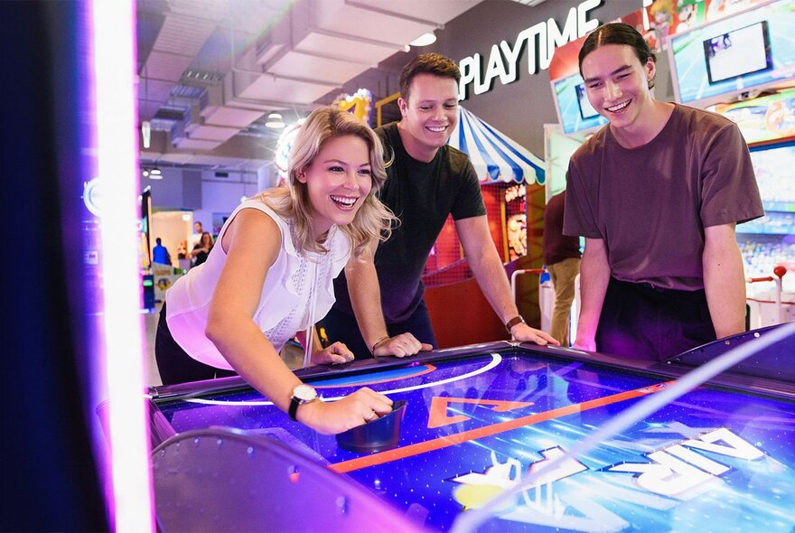 People having fun playing arcade games, at a Kingpin entertainment venue.