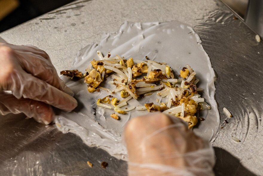 A person's hands preparing Vietnamese spring rolls.