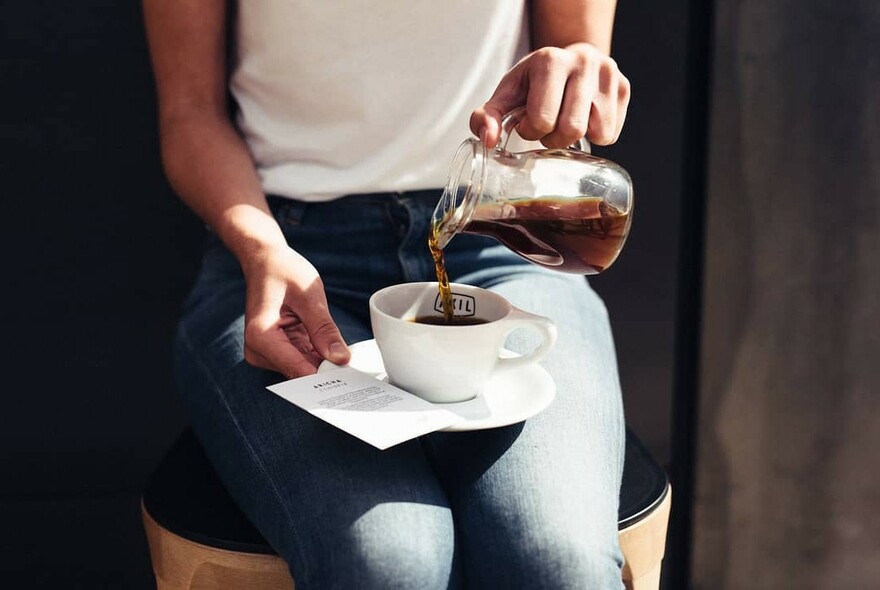 Person pouring coffee at Axil Coffee Roasters.