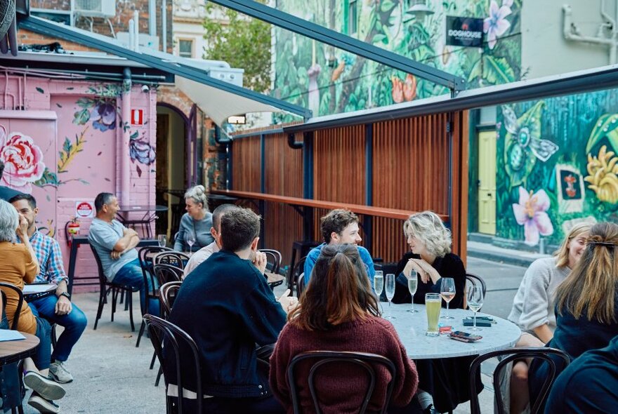 Outdoor courtyard with patrons sitting and drinking at tables and chairs.