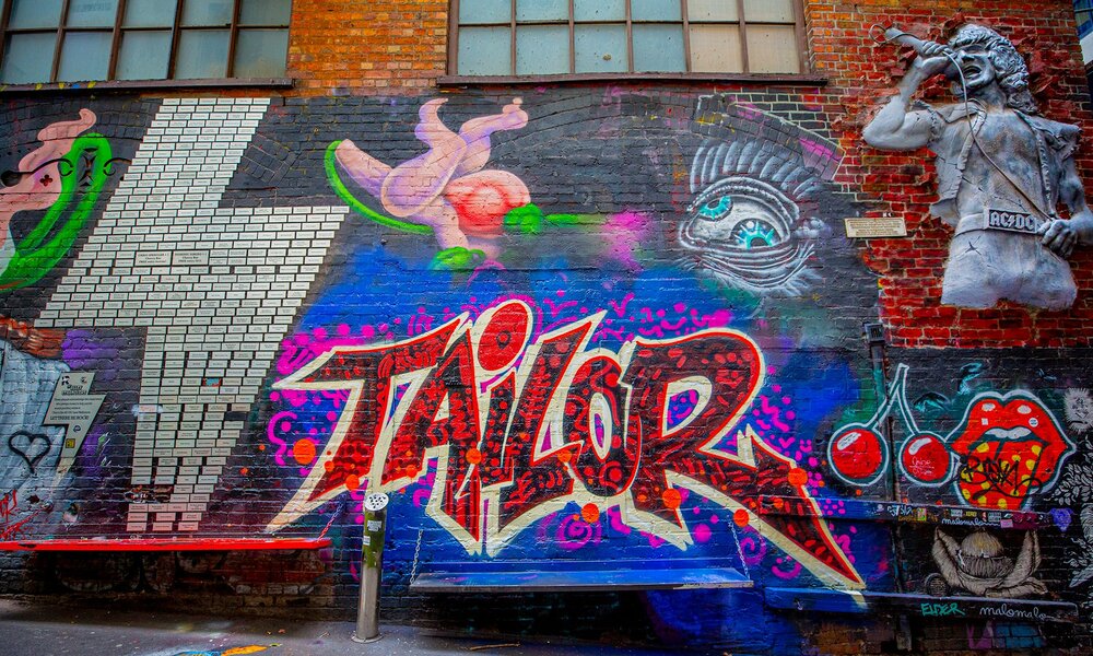 A wall of street art including a concrete bust of a singer, cherries and a lightning bolt.