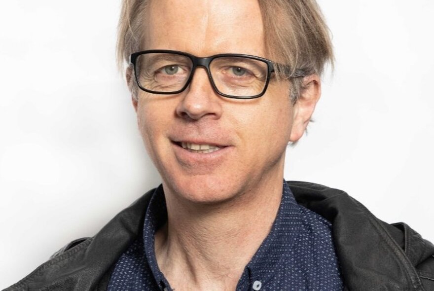 Jeff Sparrow looking amused and wearing black glasses. 