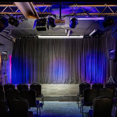 The empty spot lit stage and seating area at the theatre venue Club Voltaire. 