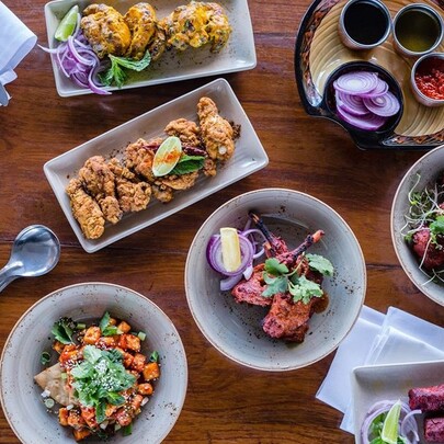 An array of Indian dishes including tandoori chicken and condiments.