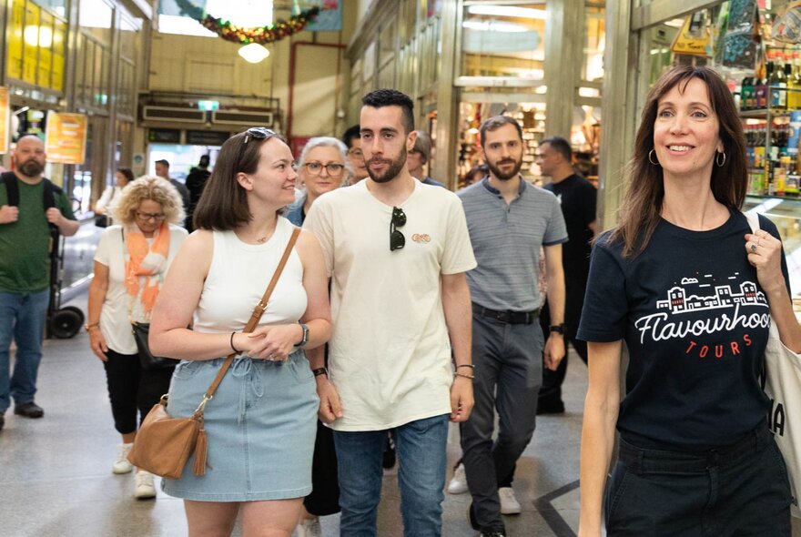 A guide leading a group of people on a tour of the deli hall at Queen Vic Market.