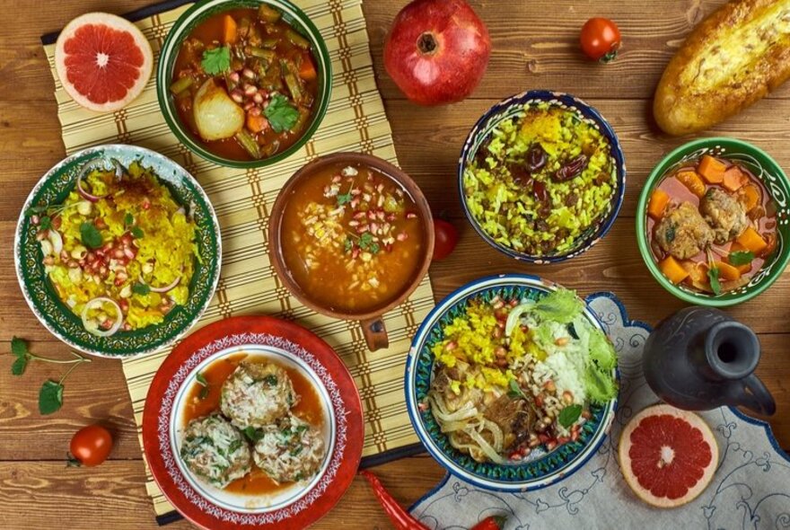 A selection of Persian dishes including rice, curries and flatbreads, on a table.