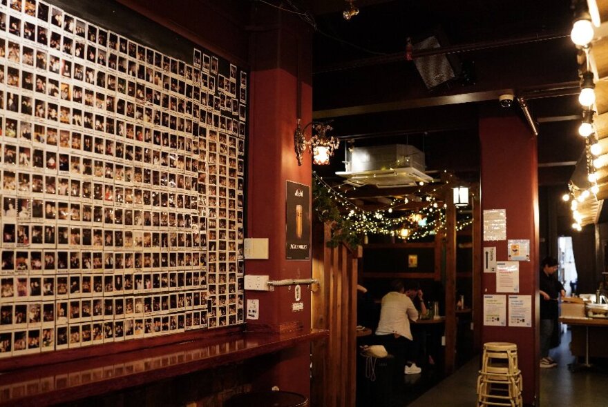 The interior of Joomak, underground Korean pub, with a perfect grid of polaroid pictures on one wall.