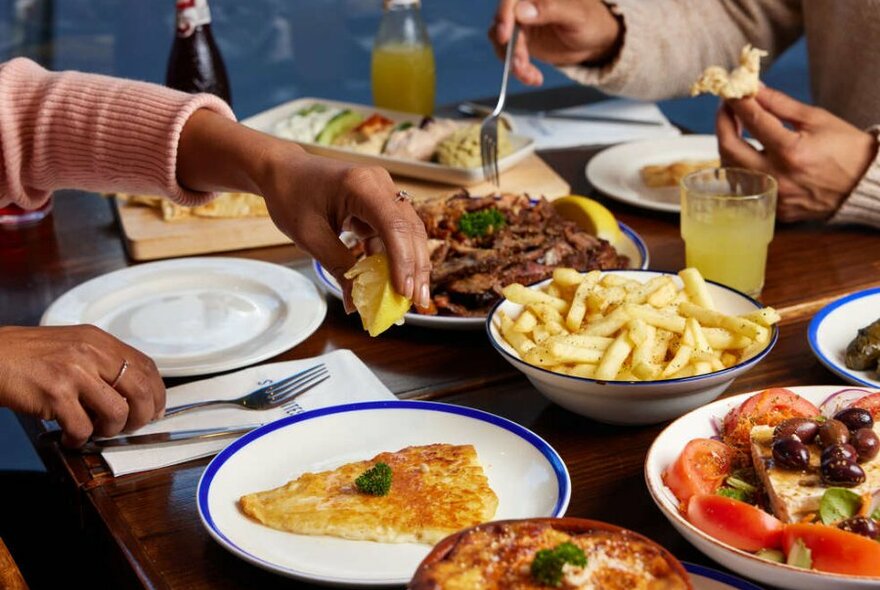 People eating from a large table of greek food