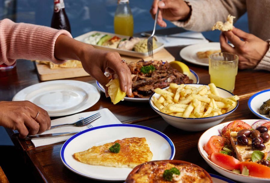 People eating from a large table of greek food