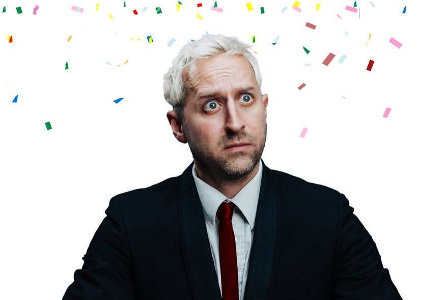 A man looking mildly horrified in a suit with illustrated confetti around his head. 