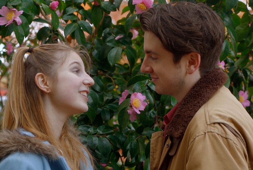 Film still from a movie depicting two people looking at each other with fondness.