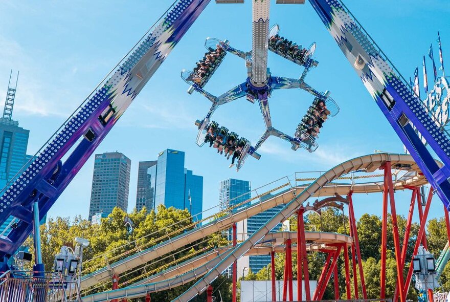 People upside down on a claw carnival ride in the city.