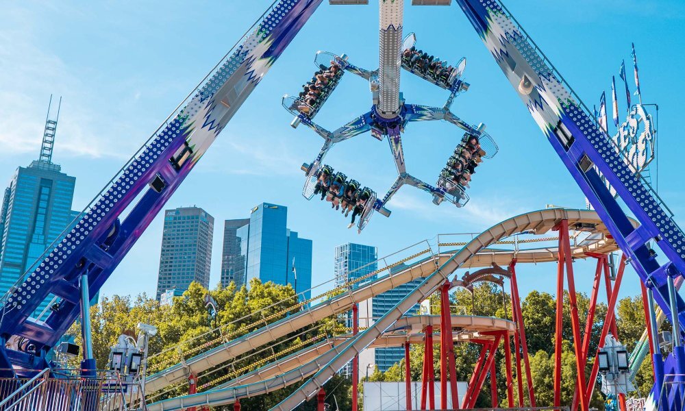 People upside down on a claw carnival ride in the city.