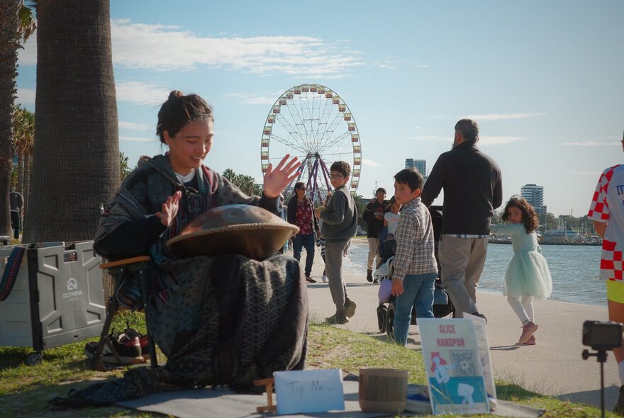 A musician playing the handpan on a grassy space next to the Yarra River in Melbourne.