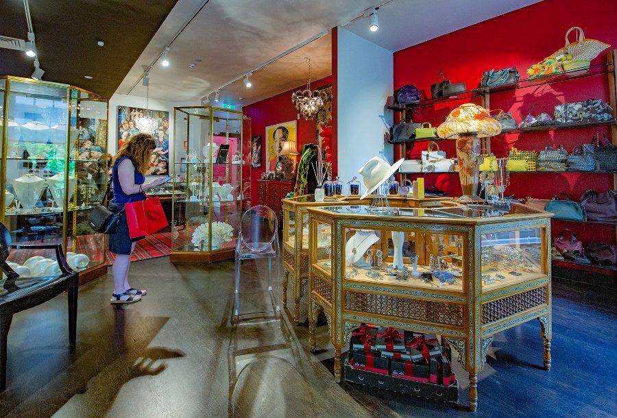A woman browsing in an eclectic boutique with jewellery display cabinets and accessories on shelves.