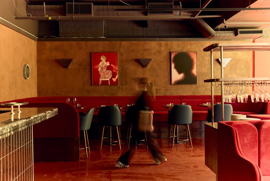 Restaurant interior with industrial styled concrete walls, visible pipes, red seating.