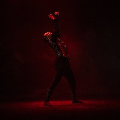 Dark image of a Dracula figure lit with red light on stage.