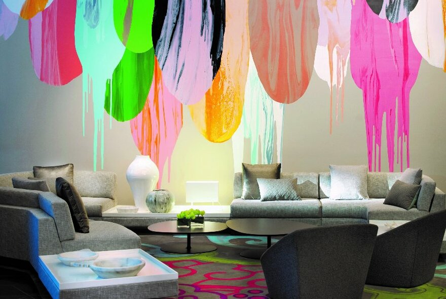 A hotel lobby with bright coloured dripping paint mural and lounges.