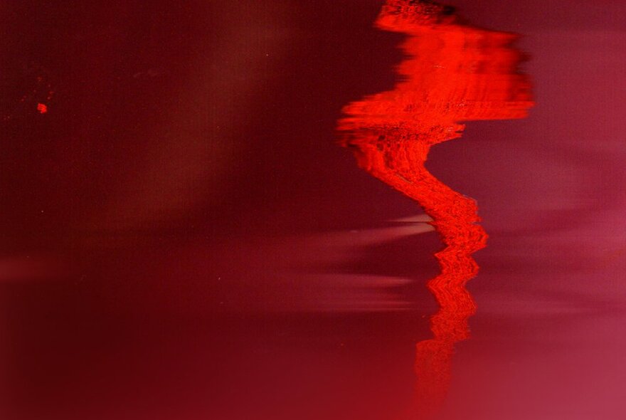 An abstract artwork mostly in shades of red, with a cloud like shape on the right side.