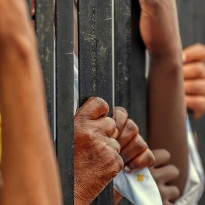 Entreating hands reaching through a fence holding fabric.