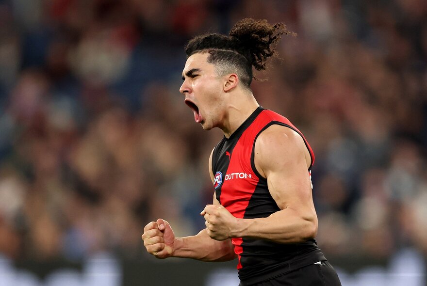 Essendon player Isaac Kako celebrating a shot with his mouth open and fists clenched. 
