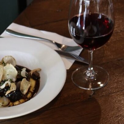 Dish of food with cutlery and glass of red wine.